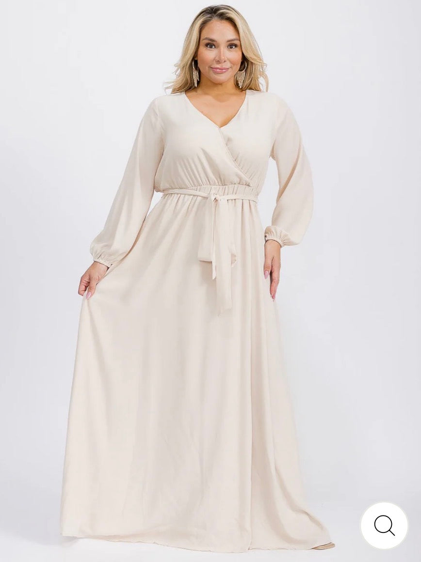 Vestido beige maxi tipo gown plus size de manga larga con escote cruzado y lazo ajustable.
