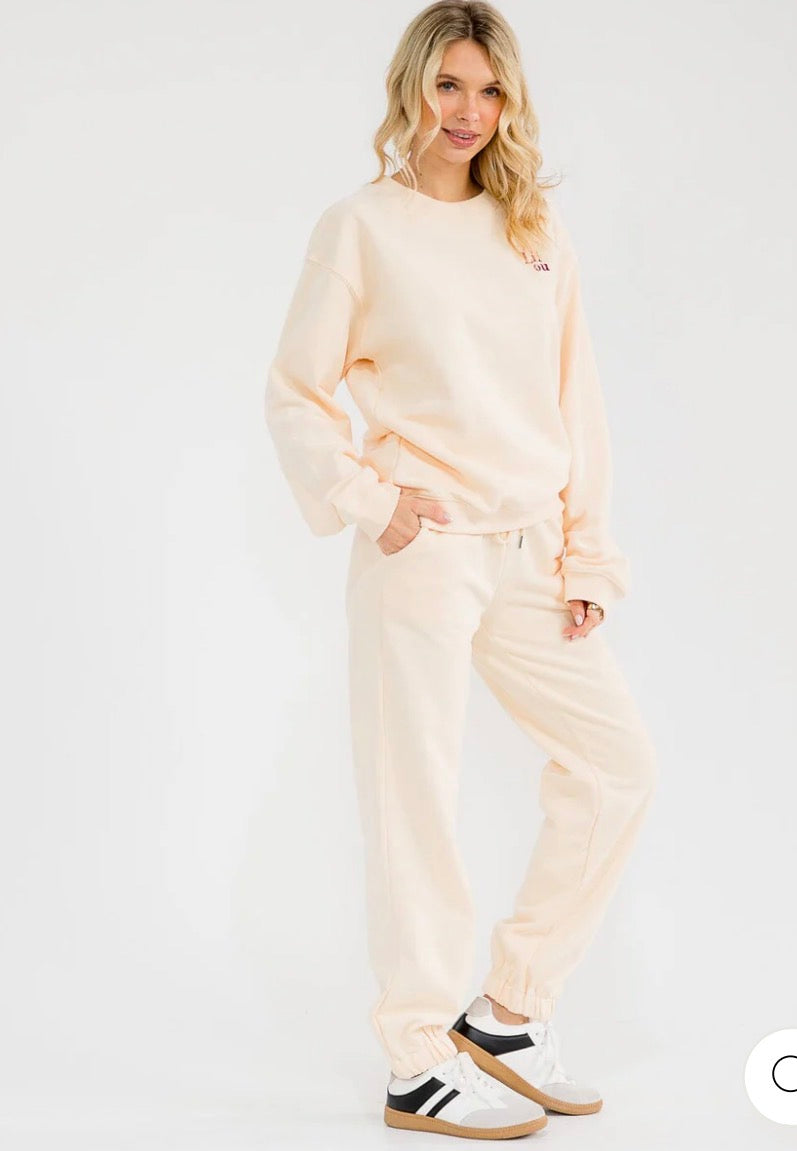 Conjunto beige de 2 piezas para mujer: suéter tipo pullover de manga larga y pantalón con cintura elástica y diseño gráfico.