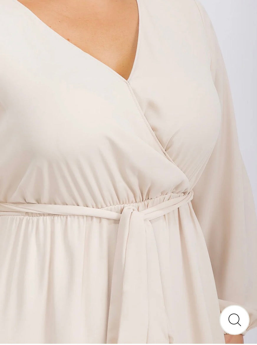 Vestido beige maxi tipo gown plus size de manga larga con escote cruzado y lazo ajustable.