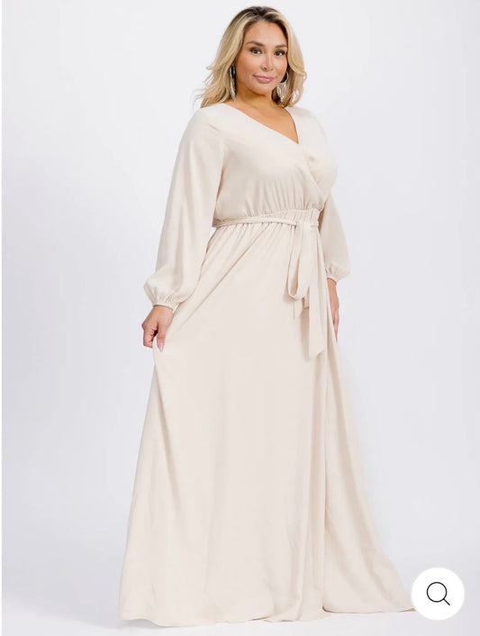 Vestido beige maxi tipo gown plus size de manga larga con escote cruzado y lazo ajustable.