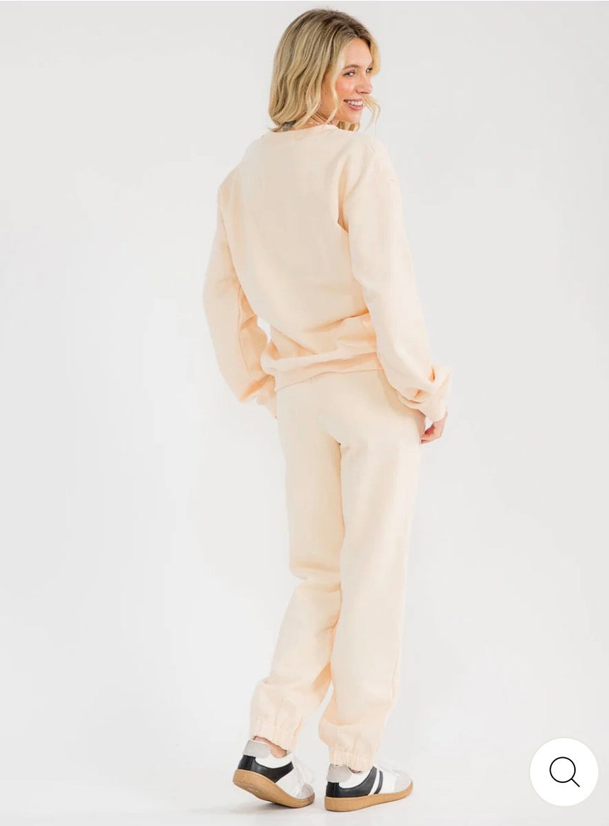 Conjunto beige de 2 piezas para mujer: suéter tipo pullover de manga larga y pantalón con cintura elástica y diseño gráfico.