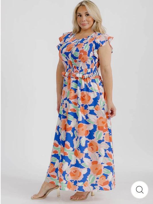 Vestido maxi floral anaranjado y azul plus size con mangas cortas con vuelo y busto tipo smock.