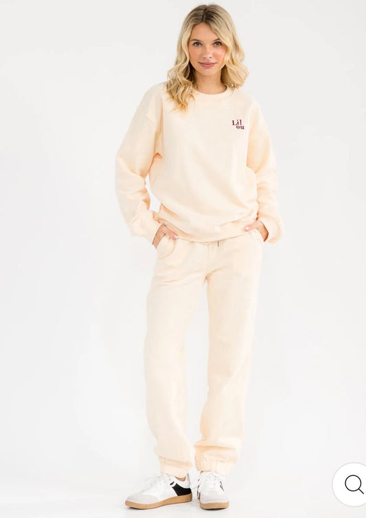 Conjunto beige de 2 piezas para mujer: suéter tipo pullover de manga larga y pantalón con cintura elástica y diseño gráfico.