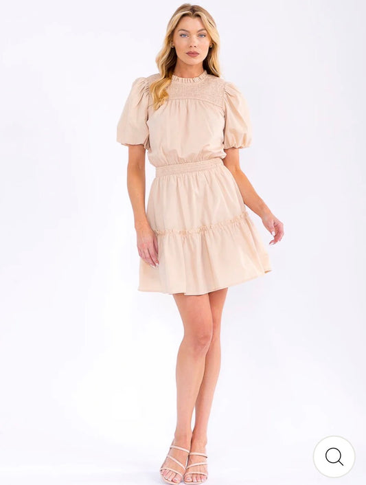 Vestido beige corto para mujer con mangas cortas tipo puff, cintura elástica y falda en capas.