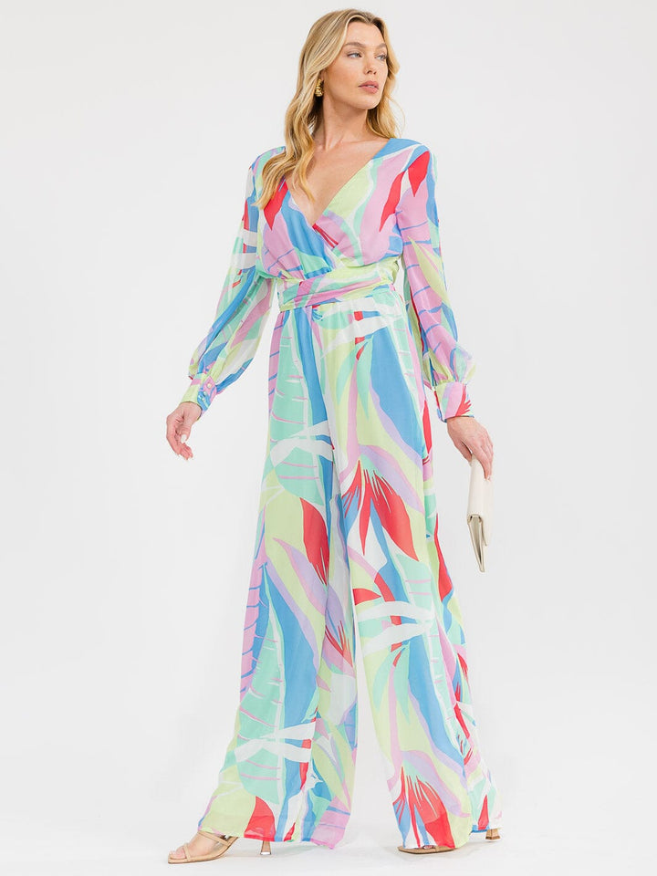 Jumpsuit pierna ancha con manga larga, escote cruzado (surplice), cintura elástica y estampado multicolor.