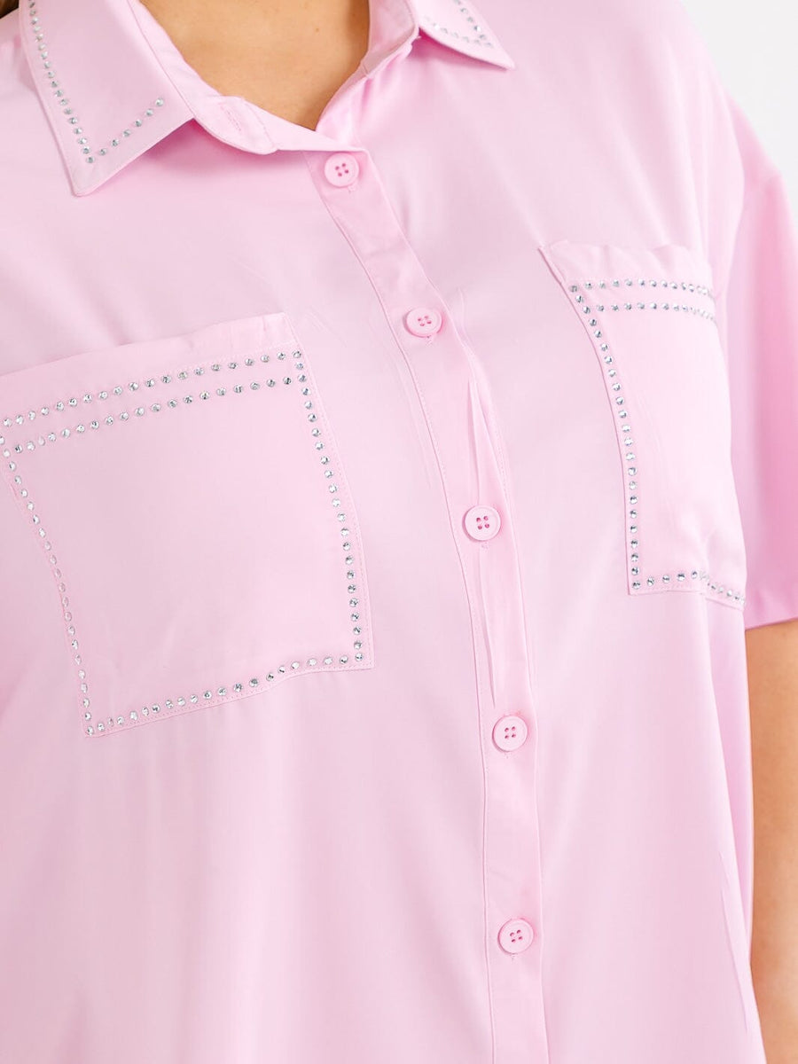 Vestido plus rosado corte holgado, con mangas cortas, botones al frente, bolsillos frontales y detalles de tachas.