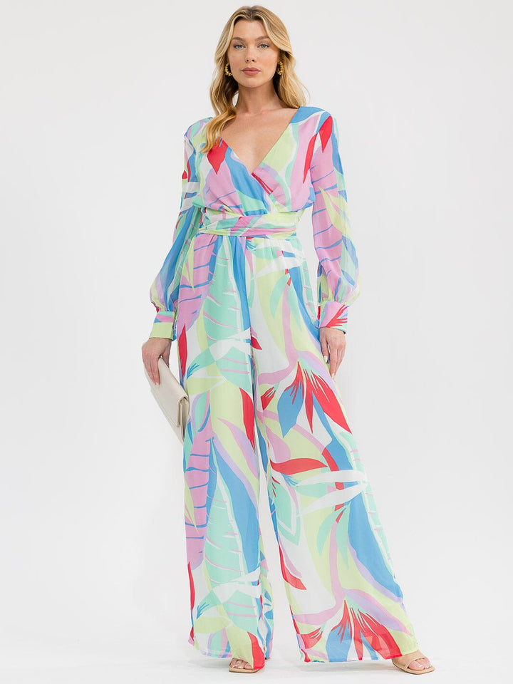 Jumpsuit pierna ancha con manga larga, escote cruzado (surplice), cintura elástica y estampado multicolor.